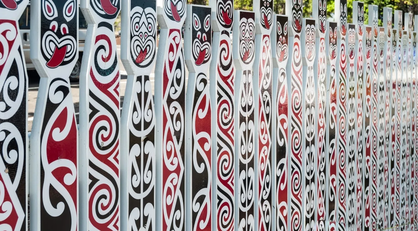 A painted palisade of red, white and black carved fence panels in a row